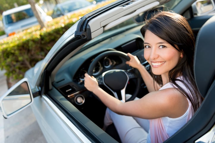 Female driver looking very happy driving a car